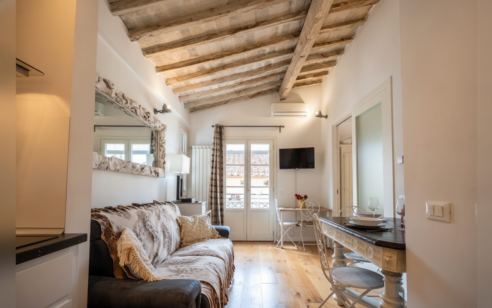 Il soggiorno dell'Appartamento di Charme, con le travi in legno e la porta finestra sul balcone