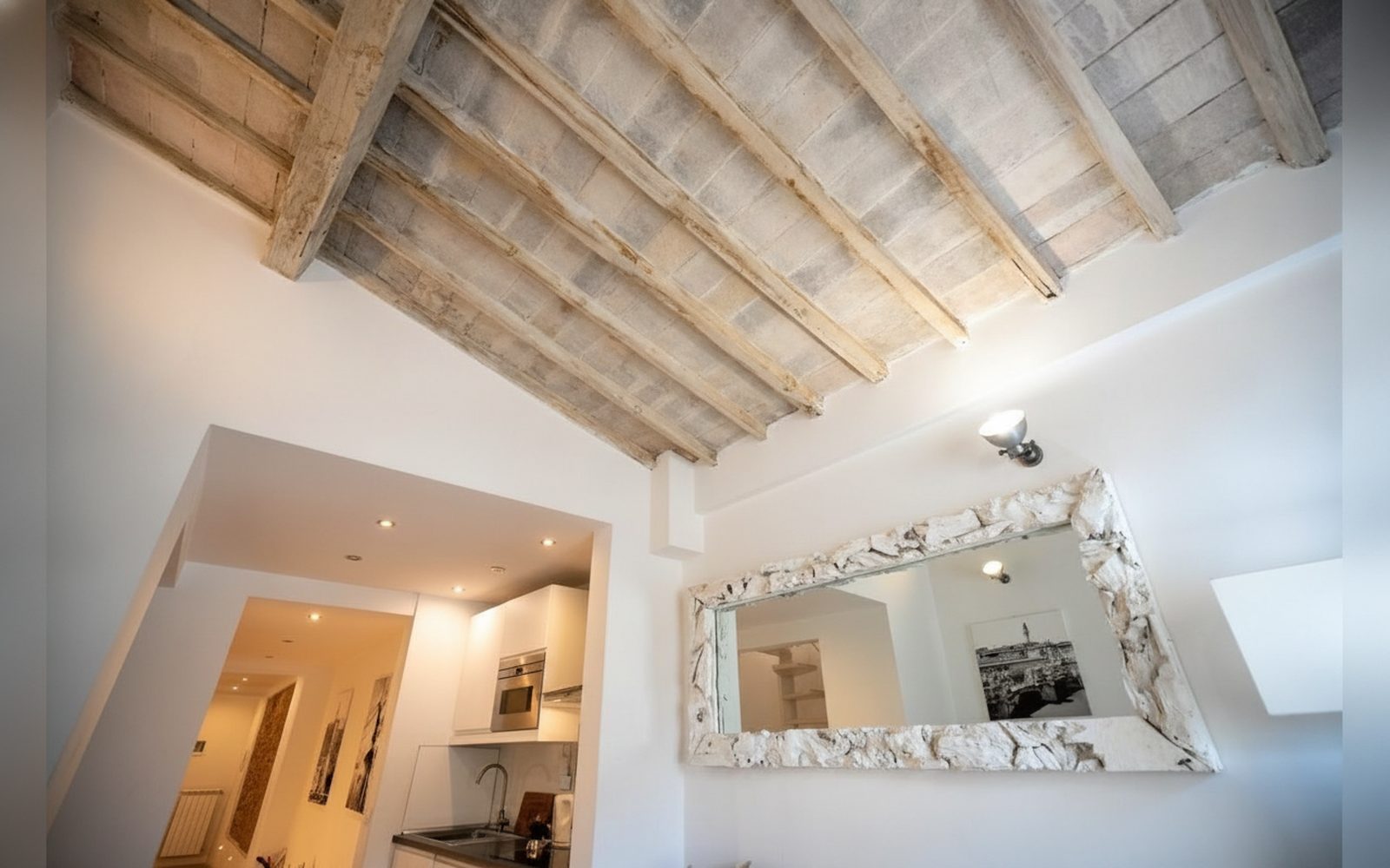 Le travi in legno sbiancato del soggiorno e lo specchio con la cornice intagliata